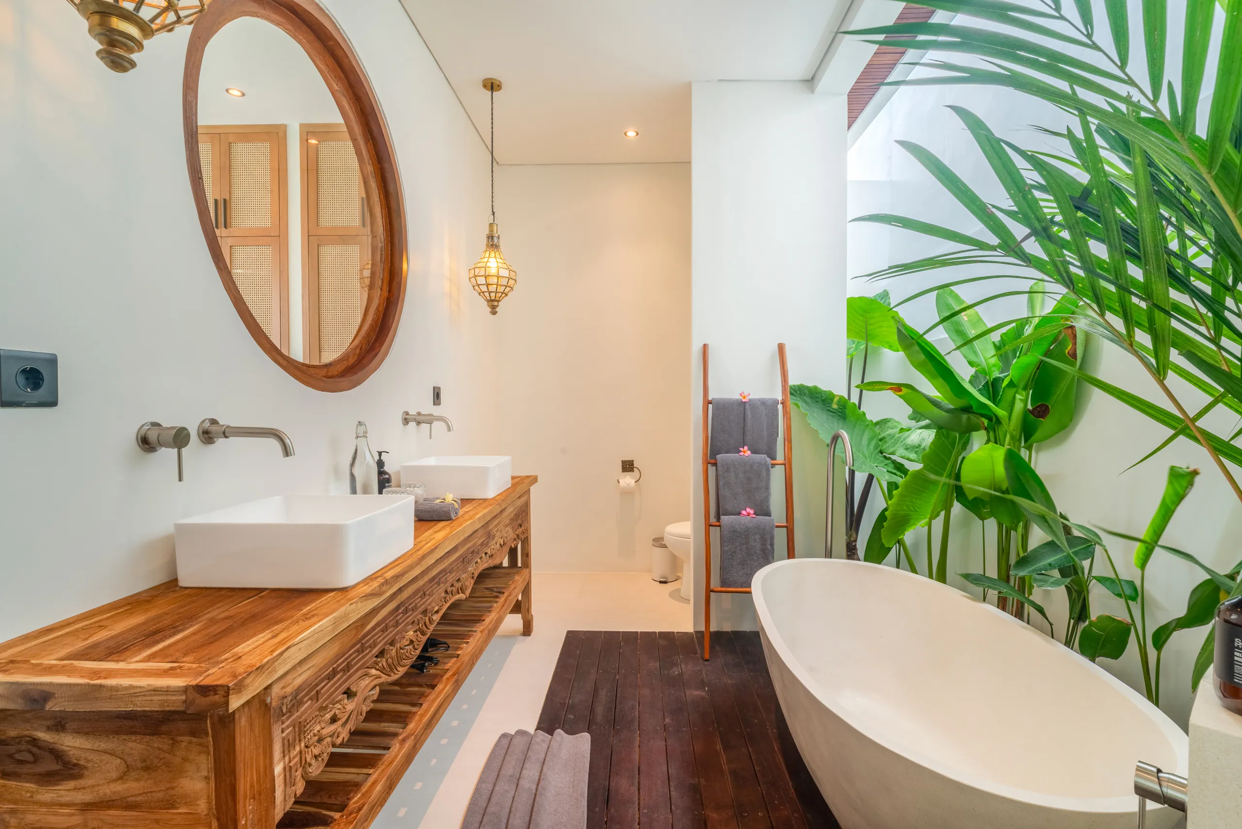 Spa bathroom with freestanding bathtub, teak vanity, round mirror and lantern pendant at Villa Sofra