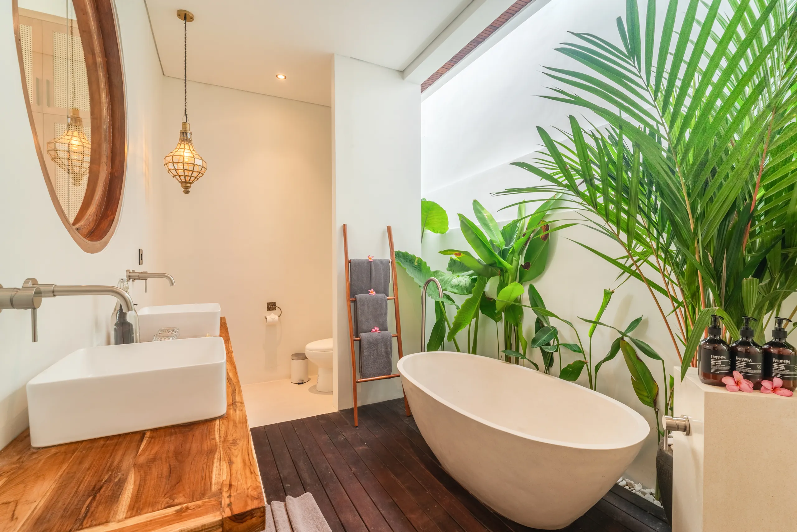 En-suite bathroom with freestanding bathtub, golden lantern and tropical plants at Villa Sofra