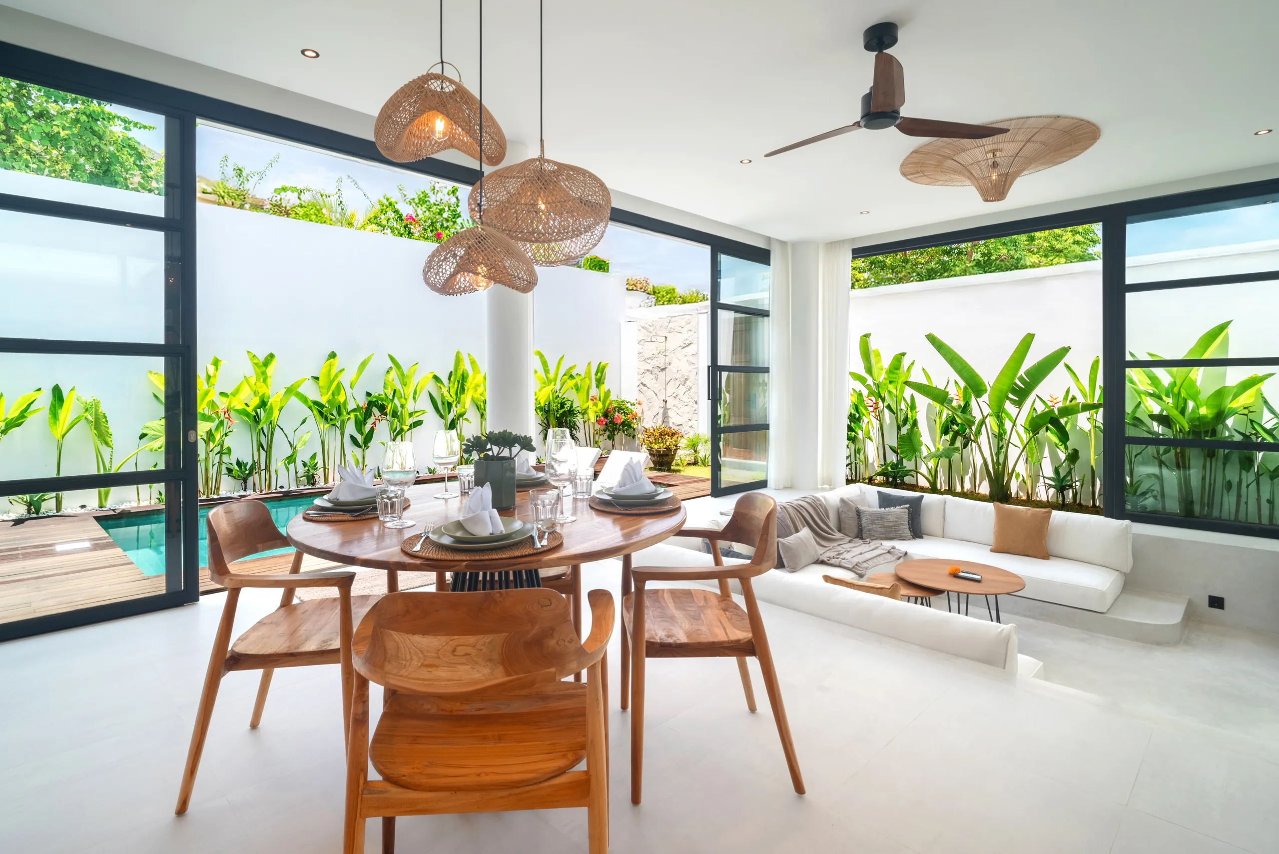 Open-plan dining and living room with tropical garden and pool view at Villa Sofra