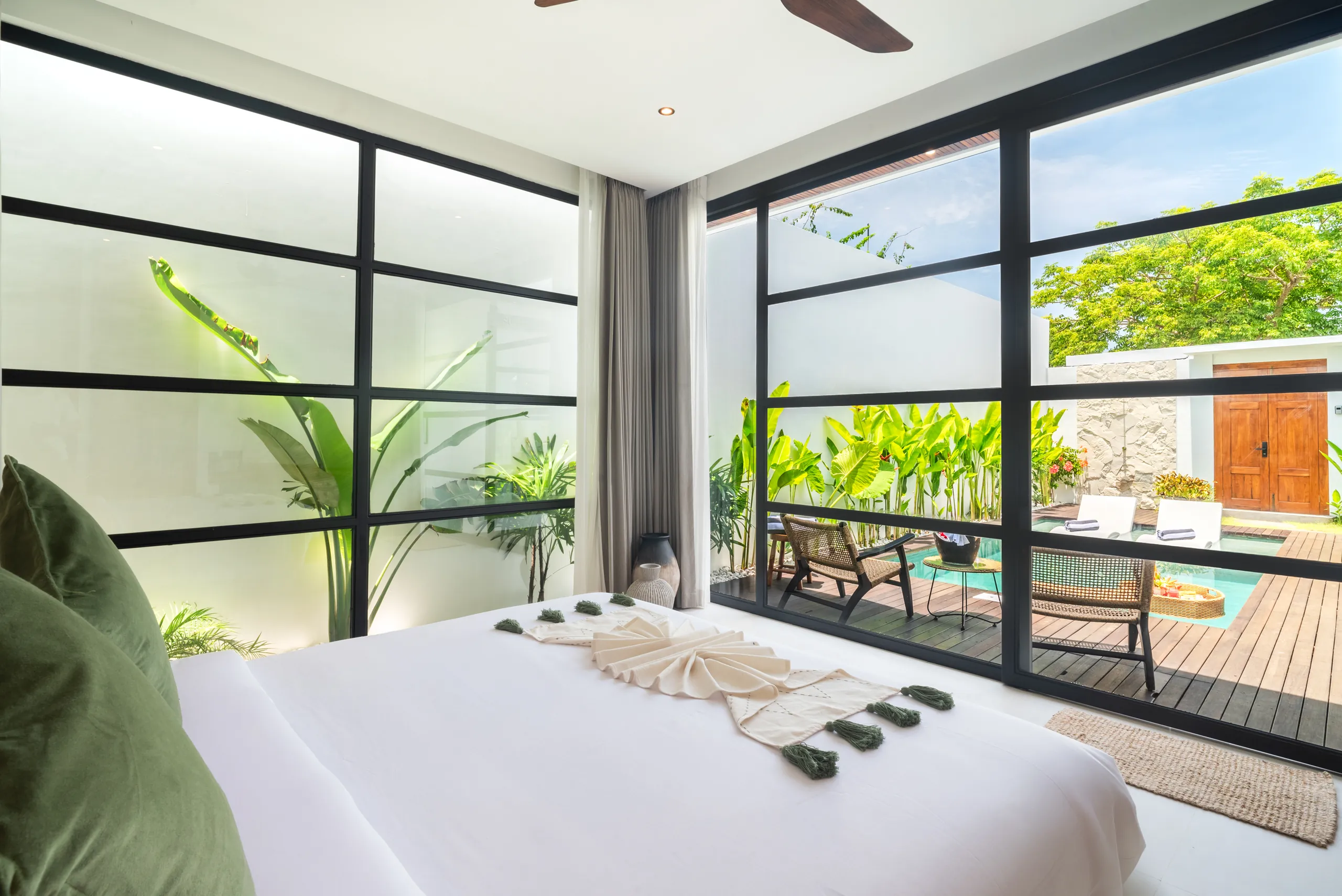 View of the private pool and teak deck through bedroom floor-to-ceiling glass at Villa Sofra