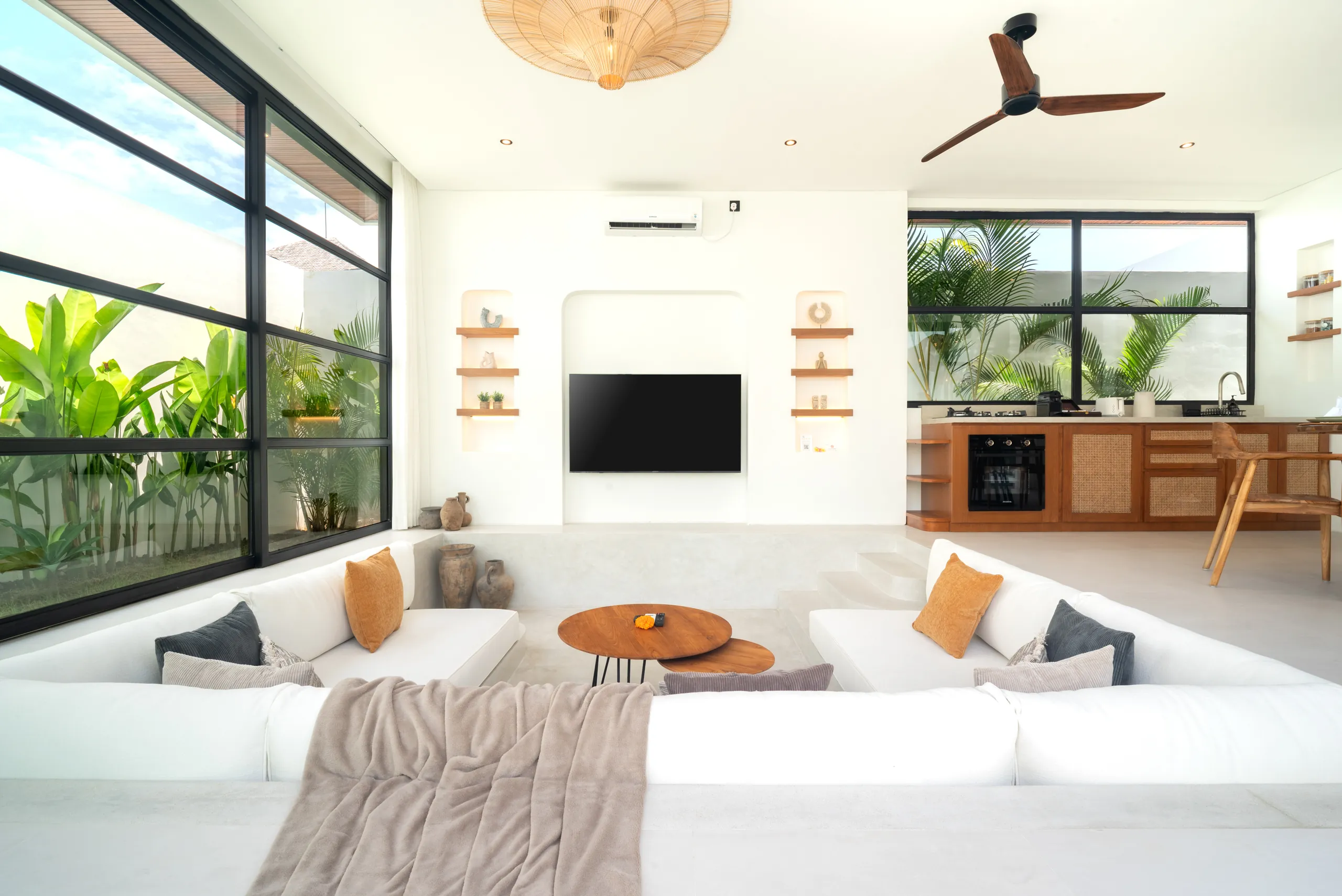 Open-plan sunken lounge, dining area and pool view through glass walls at Villa Sofra