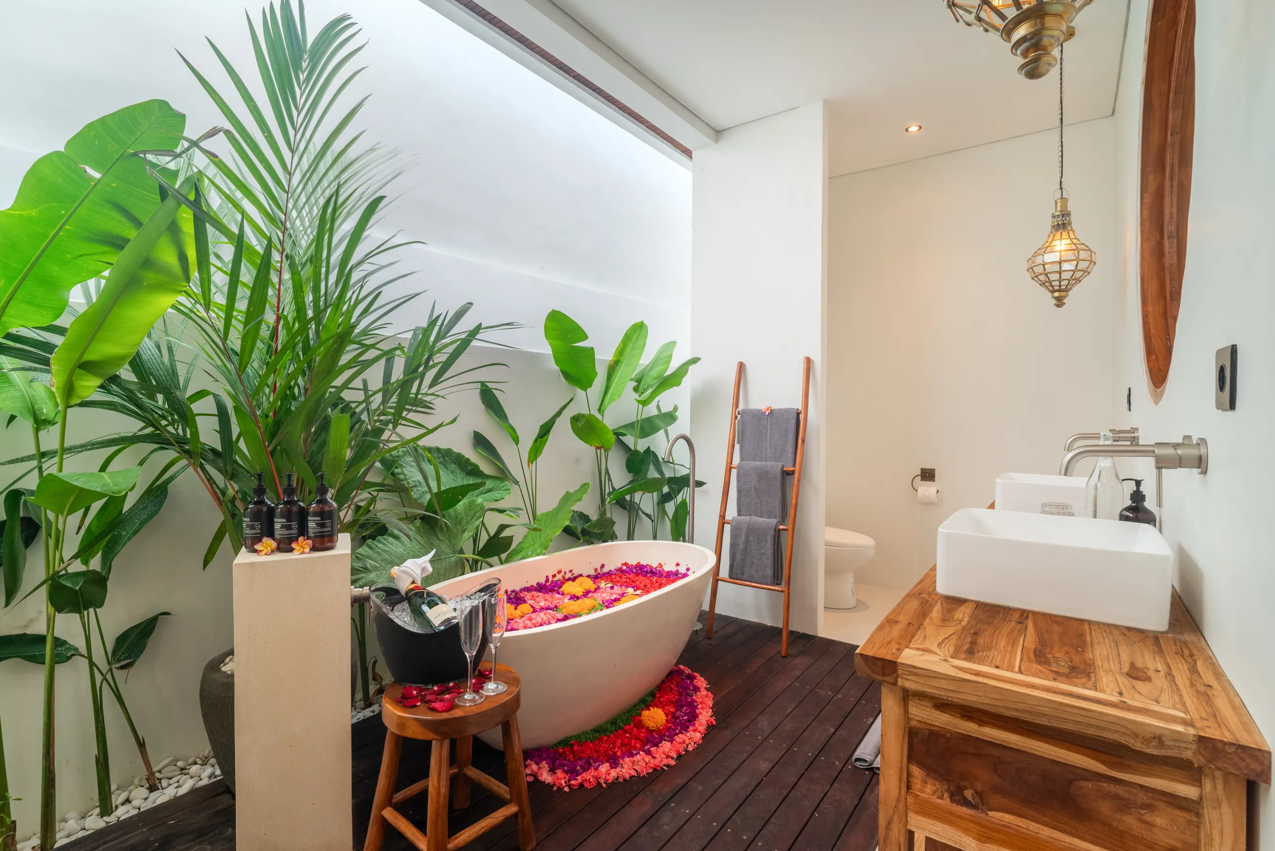 Semi-outdoor bathroom with freestanding bathtub filled with flower petals at Villa Sofra