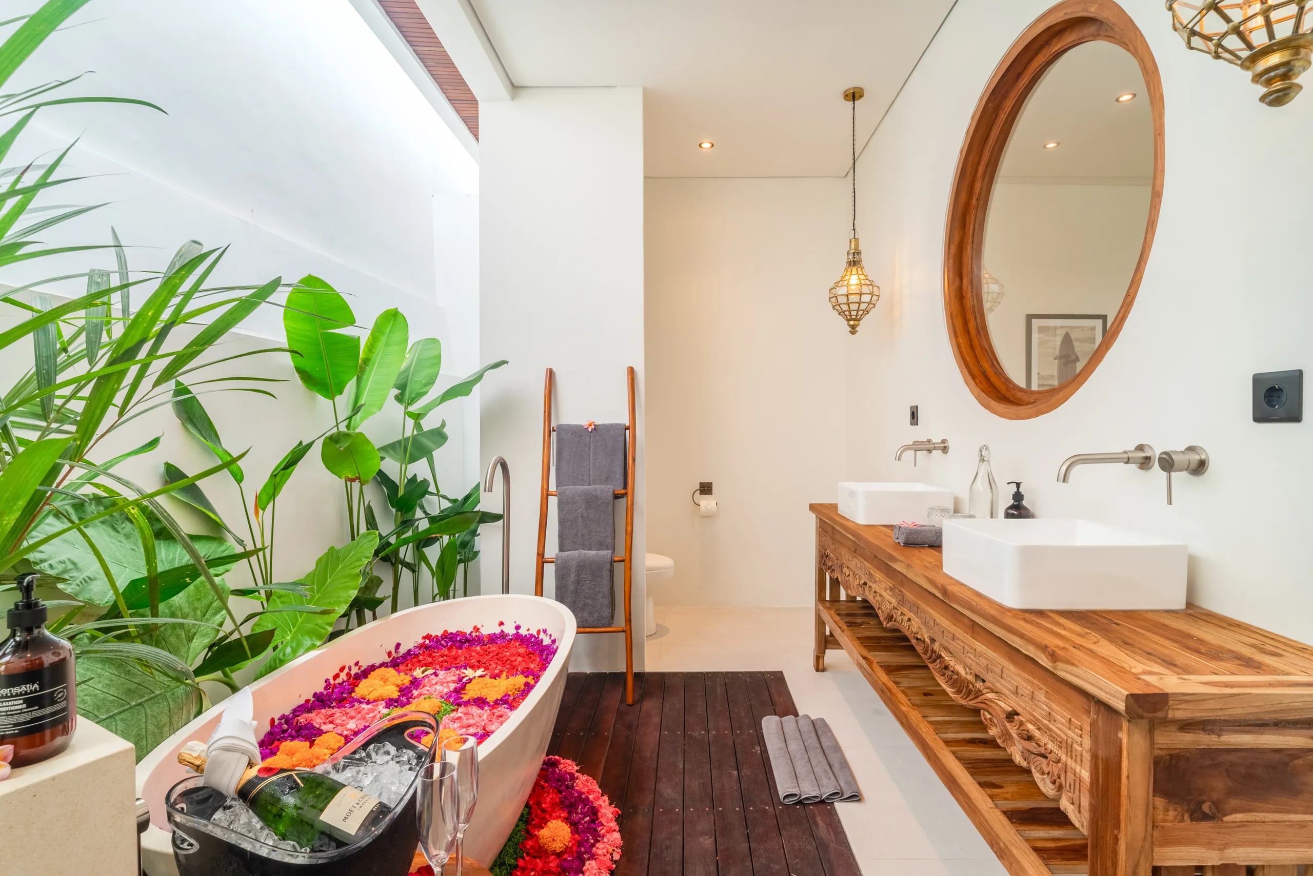 Spa-style bathroom with teak vanity, round mirror and flower petal bathtub at Villa Sofra